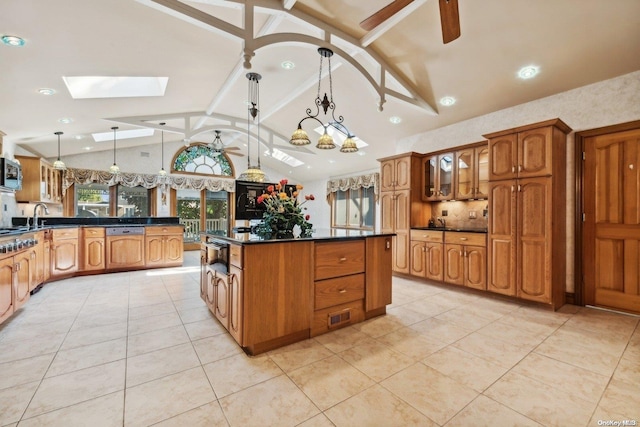 kitchen featuring vaulted ceiling with skylight, ceiling fan, pendant lighting, a kitchen island, and light tile patterned flooring