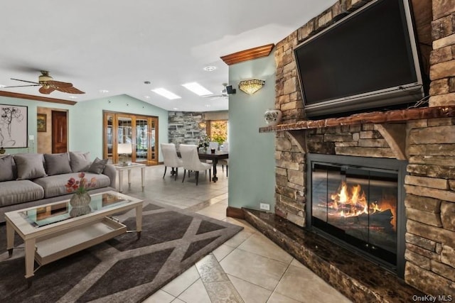 tiled living room featuring a stone fireplace, ceiling fan, and lofted ceiling