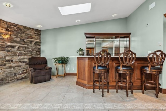 bar featuring vaulted ceiling and light tile patterned flooring