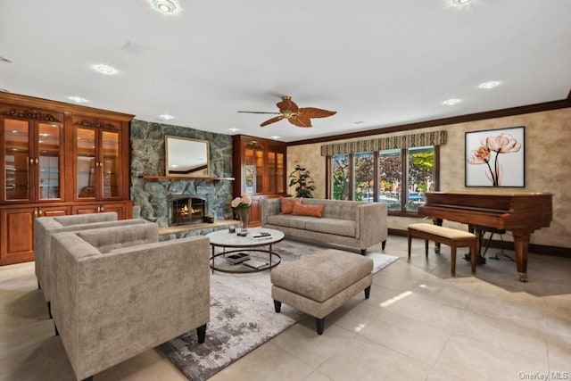 living room featuring crown molding, a fireplace, ceiling fan, and light tile patterned flooring