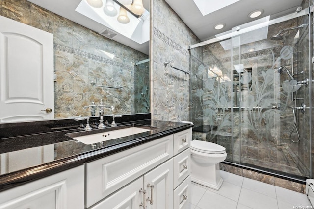 bathroom featuring a skylight, walk in shower, vanity, tile walls, and tile patterned flooring