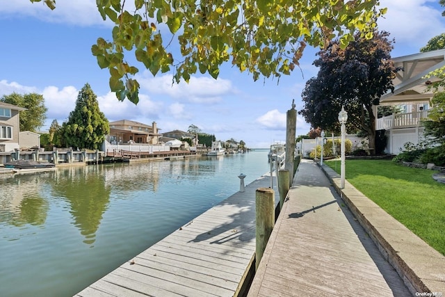 view of dock with a lawn and a water view