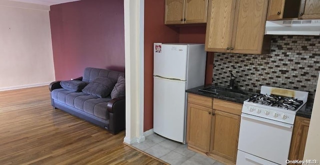 kitchen with decorative backsplash, white appliances, extractor fan, sink, and light hardwood / wood-style flooring