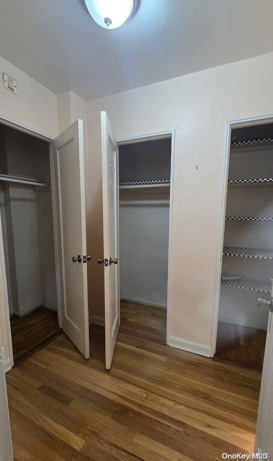 unfurnished bedroom featuring dark hardwood / wood-style flooring and two closets