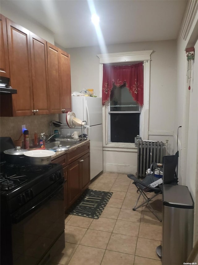 kitchen featuring backsplash, radiator, black gas stove, sink, and light tile patterned floors