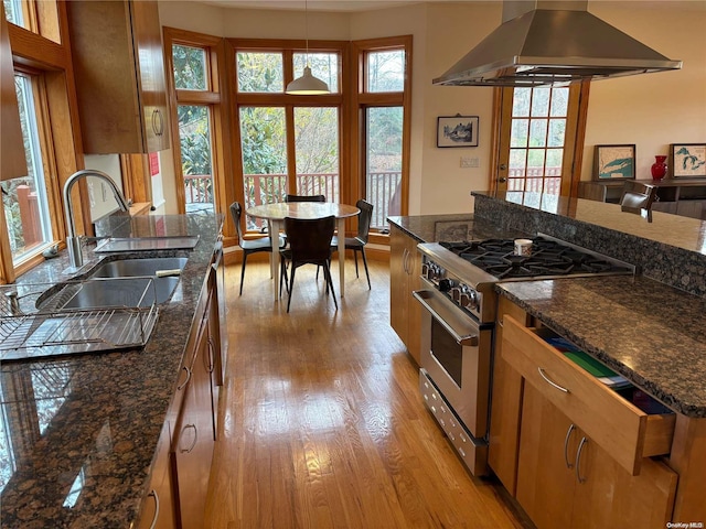 kitchen featuring sink, light hardwood / wood-style flooring, high end stove, dark stone counters, and island range hood