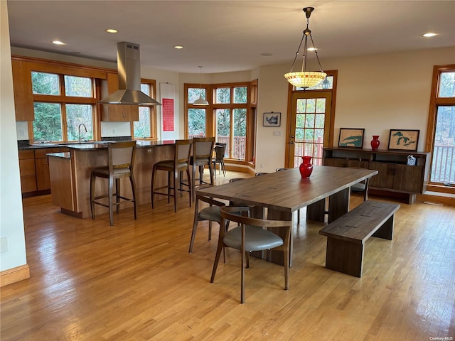 dining room featuring light wood-type flooring, a notable chandelier, and sink