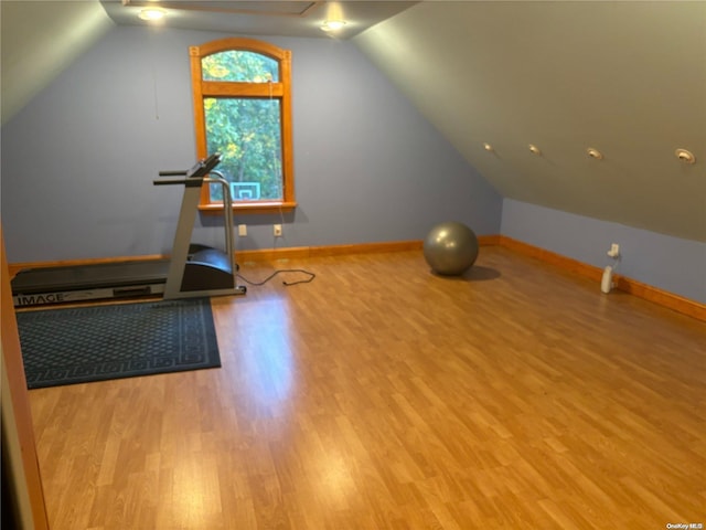 workout area with light wood-type flooring and vaulted ceiling