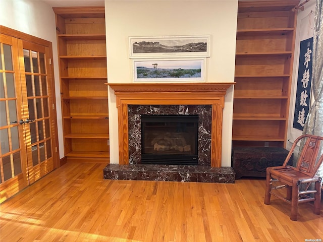 unfurnished living room featuring light hardwood / wood-style floors, built in features, and a fireplace