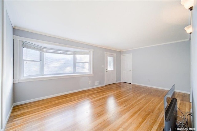 spare room with light wood-type flooring and ornamental molding