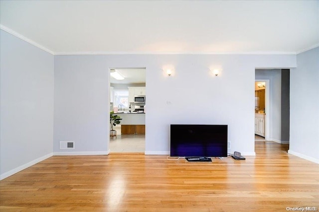 unfurnished living room with ornamental molding, sink, and light hardwood / wood-style flooring