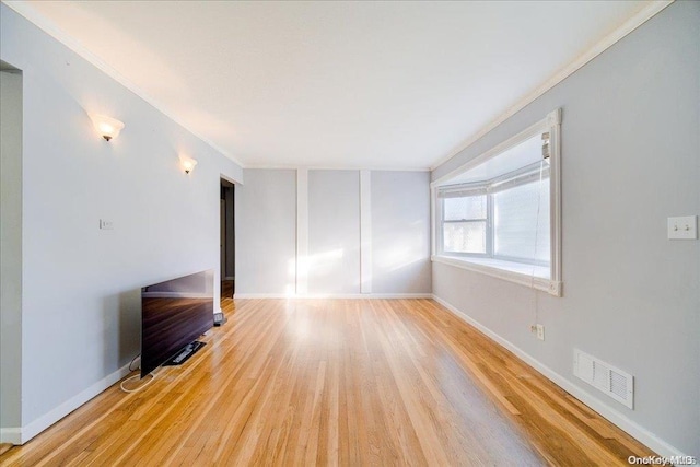 unfurnished living room featuring crown molding and hardwood / wood-style floors