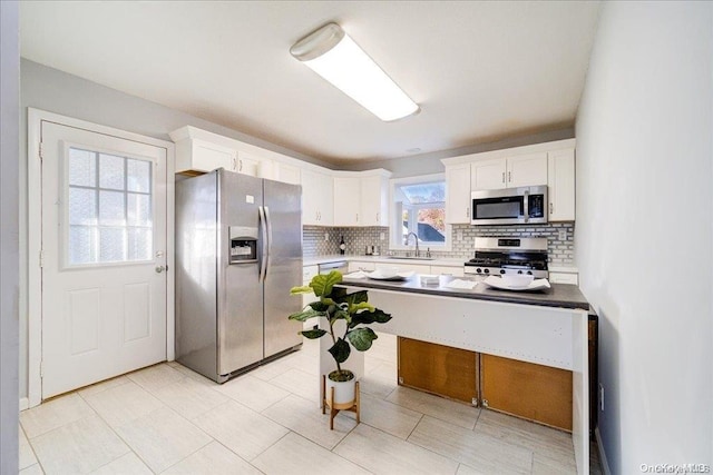 kitchen featuring tasteful backsplash, stainless steel appliances, sink, white cabinets, and light tile patterned flooring