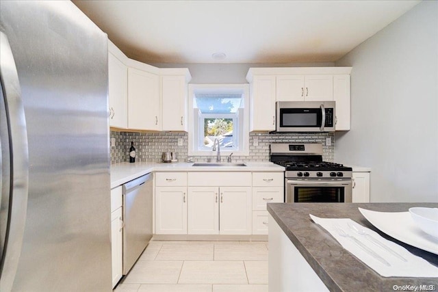 kitchen featuring backsplash, sink, light tile patterned floors, white cabinetry, and stainless steel appliances