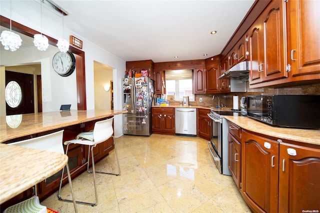 kitchen featuring decorative backsplash, pendant lighting, stainless steel appliances, and sink