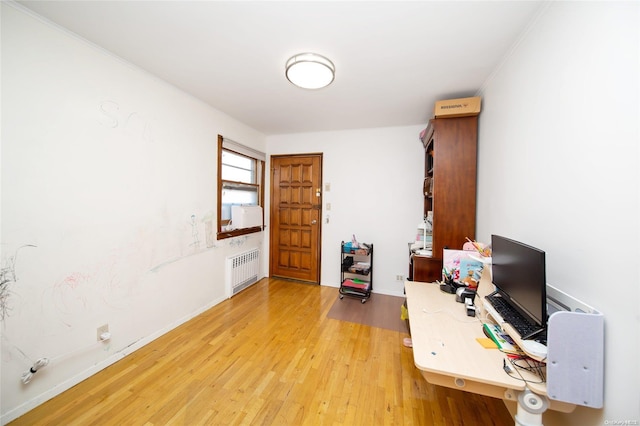 home office featuring crown molding, radiator heating unit, and light hardwood / wood-style flooring