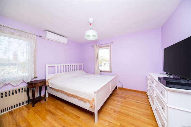 bedroom with light hardwood / wood-style floors, radiator heating unit, and a wall mounted AC