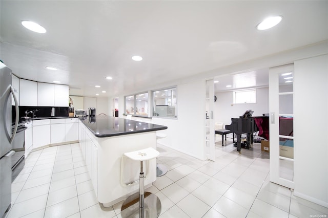 kitchen featuring a kitchen bar, white cabinetry, and light tile patterned floors