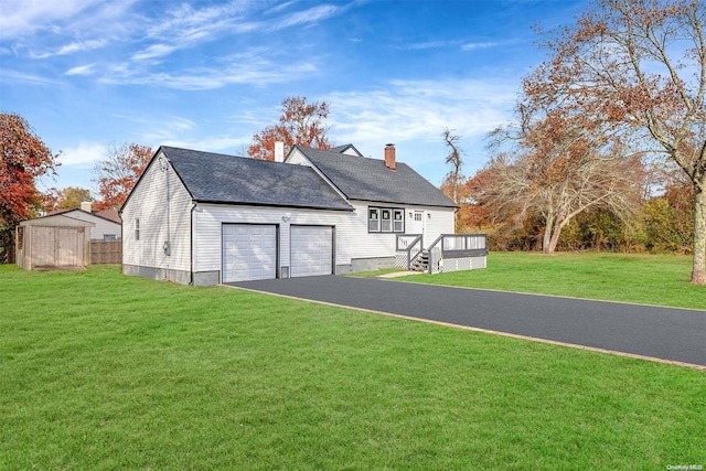 back of house with a garage, a wooden deck, and a lawn