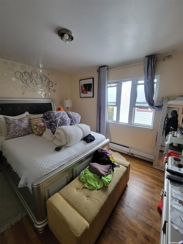 bedroom with baseboard heating and wood-type flooring