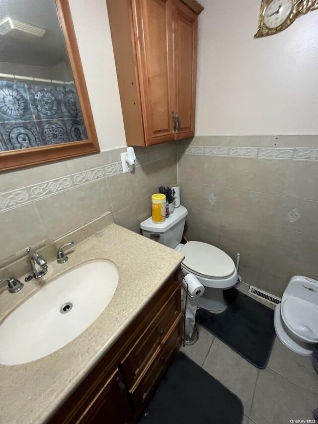 bathroom featuring tile patterned flooring, vanity, toilet, and tile walls