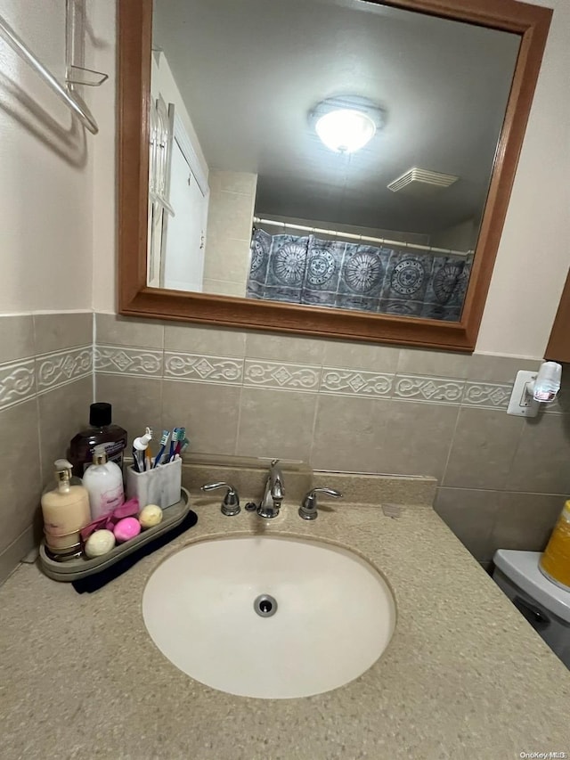 bathroom with toilet, sink, and tile walls