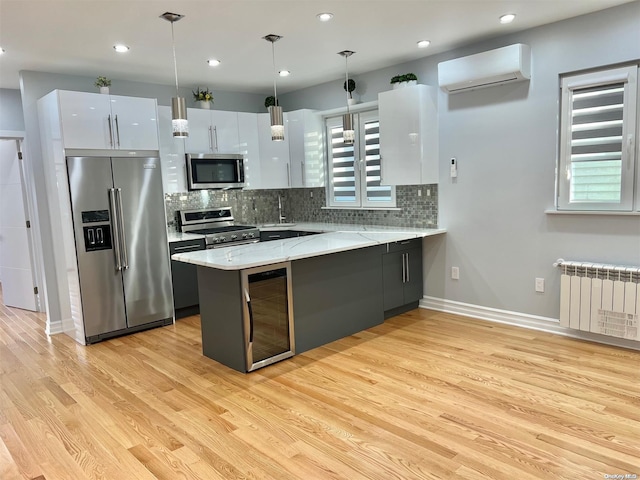 kitchen with pendant lighting, radiator, white cabinetry, stainless steel appliances, and a wall mounted air conditioner