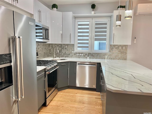 kitchen featuring decorative light fixtures, a wall mounted AC, gray cabinets, stainless steel appliances, and white cabinets