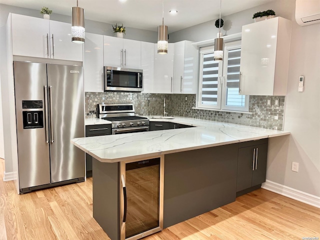 kitchen with wine cooler, decorative light fixtures, a wall unit AC, stainless steel appliances, and white cabinets