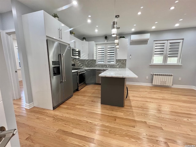 kitchen featuring an AC wall unit, radiator, pendant lighting, a breakfast bar, and stainless steel appliances