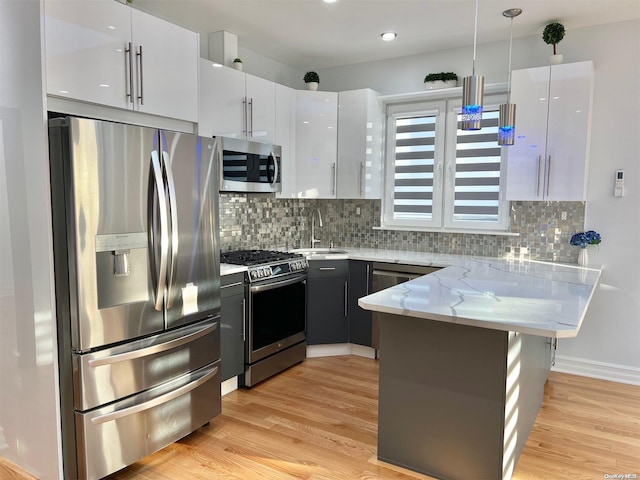 kitchen featuring appliances with stainless steel finishes, pendant lighting, sink, white cabinets, and kitchen peninsula