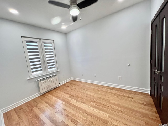 unfurnished bedroom featuring radiator heating unit, light hardwood / wood-style floors, and ceiling fan