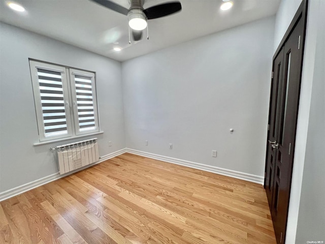 unfurnished bedroom featuring ceiling fan, radiator, and light hardwood / wood-style floors