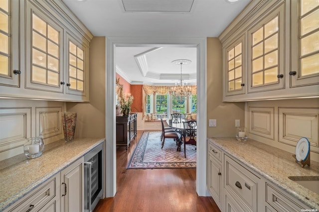 bar featuring light stone countertops, a tray ceiling, beverage cooler, a chandelier, and dark hardwood / wood-style floors