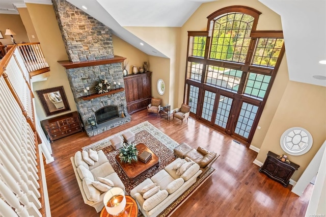 living room with a stone fireplace, wood-type flooring, and high vaulted ceiling