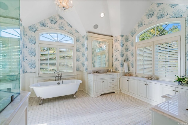 bathroom featuring a bathing tub, an inviting chandelier, a wealth of natural light, and lofted ceiling