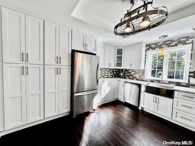 kitchen with white cabinetry, sink, stainless steel appliances, dark hardwood / wood-style flooring, and decorative light fixtures