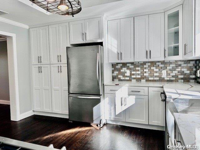 kitchen featuring stainless steel refrigerator, white cabinetry, light stone countertops, dark hardwood / wood-style floors, and crown molding