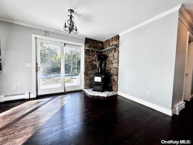 unfurnished living room featuring a wood stove, crown molding, dark wood-type flooring, and a baseboard radiator