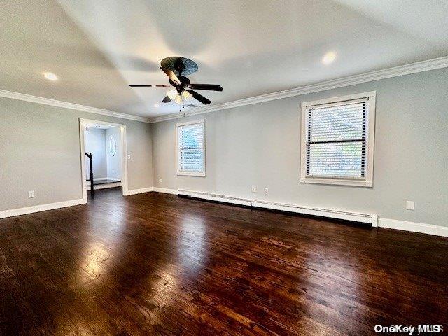 spare room with crown molding, ceiling fan, dark wood-type flooring, and a baseboard heating unit