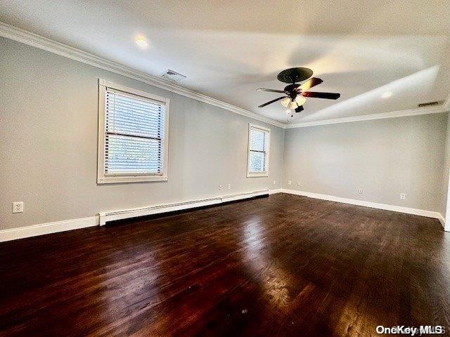 empty room with hardwood / wood-style floors, crown molding, a wealth of natural light, and a baseboard radiator