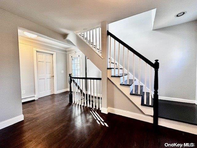 staircase featuring a textured ceiling, wood-type flooring, and baseboard heating