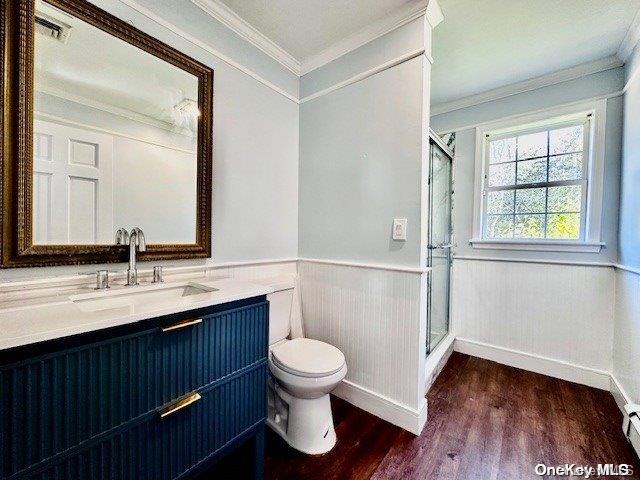 bathroom with vanity, ornamental molding, an enclosed shower, and hardwood / wood-style flooring