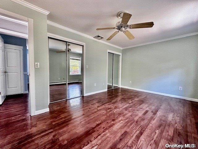 unfurnished bedroom featuring a baseboard heating unit, ceiling fan, dark hardwood / wood-style floors, and ornamental molding