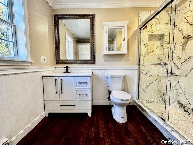 bathroom with vanity, hardwood / wood-style flooring, toilet, ornamental molding, and an enclosed shower