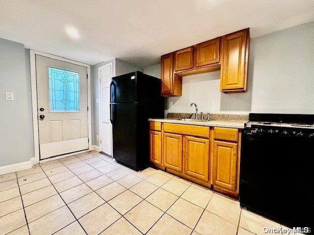 kitchen featuring sink, light tile patterned floors, and black appliances