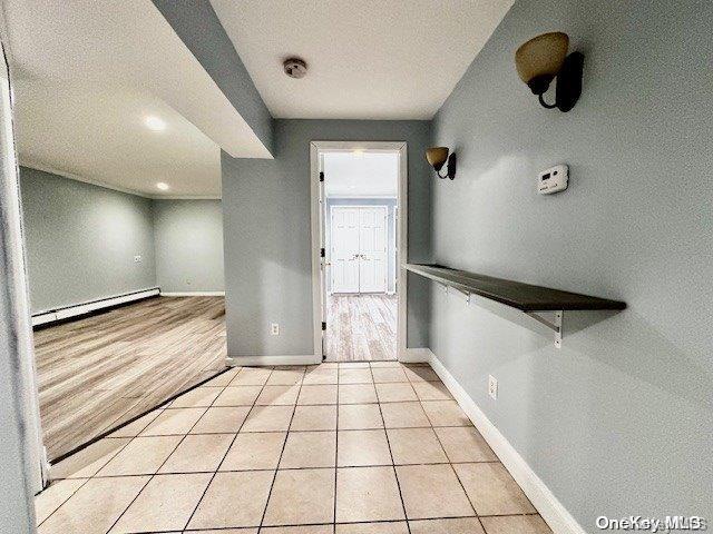 foyer entrance featuring baseboard heating, a textured ceiling, and light wood-type flooring