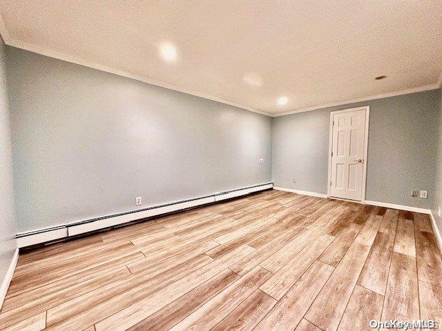 spare room with baseboard heating, crown molding, light hardwood / wood-style flooring, and a textured ceiling