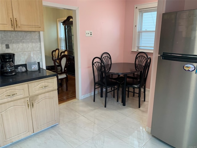 kitchen with decorative backsplash, light brown cabinetry, light tile patterned floors, and stainless steel refrigerator