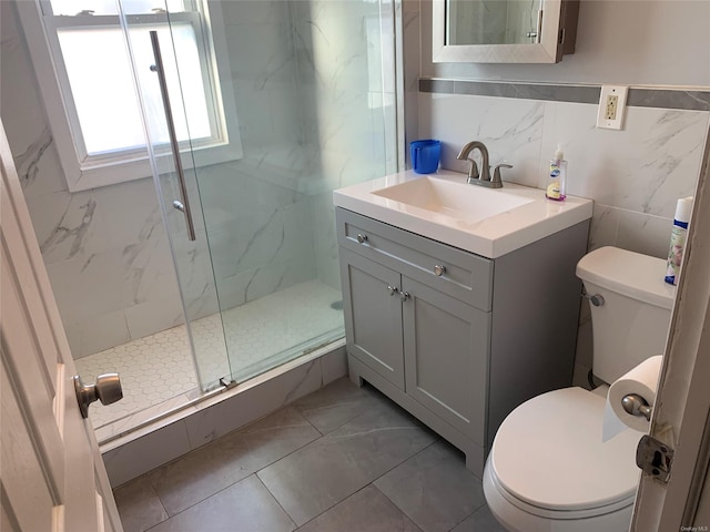 bathroom with vanity, toilet, a shower with door, and tile walls